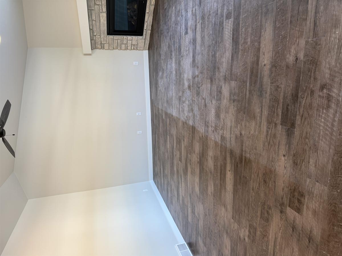 Living room floor with construction dust and stone corner fireplace — ceiling fan visible overhead