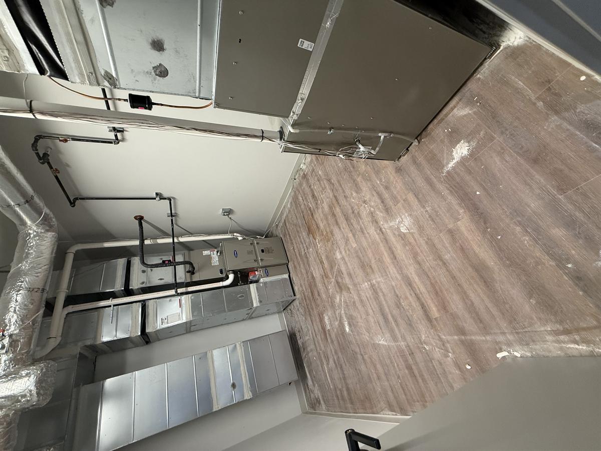 Mechanical room with HVAC ductwork and floor covered in construction grime before cleaning