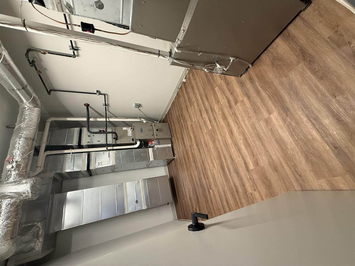 Mechanical room with Carrier HVAC equipment and clean vinyl plank floor after post-construction clean