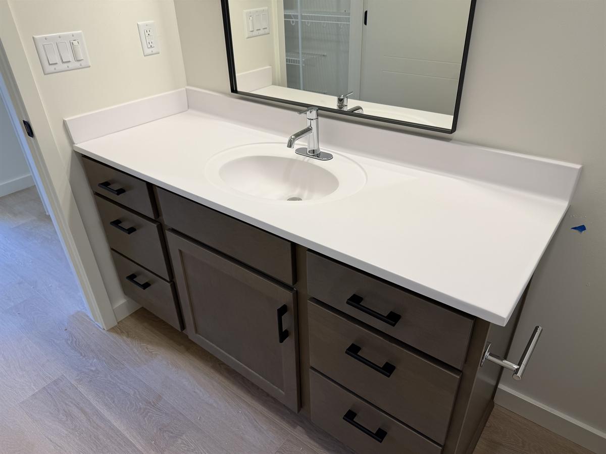 Bathroom vanity with dark shaker cabinet, white countertop, and undermount sink after cleaning