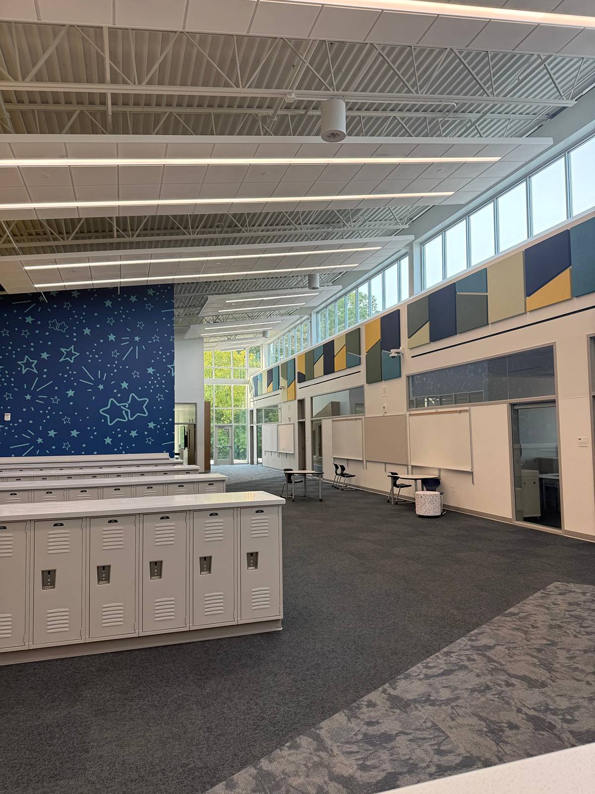 Large open commons with rows of white lockers, clerestory windows, and clean carpet